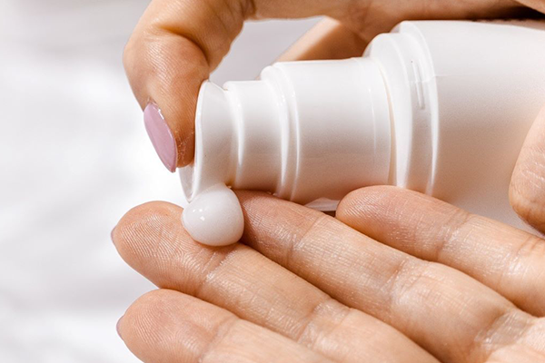 Fyller hand med lotion från flaska för att behandla atopiskt eksem.