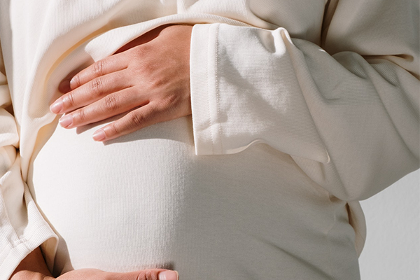 Gravid kvinna som håller på sin mage