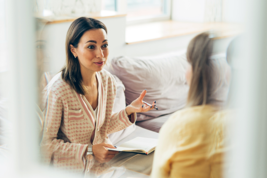 Två kvinnor som sitter i en soffa och pratar med varandra