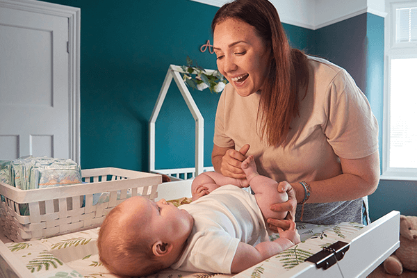 Mamma och bebis busar vid skötbordet