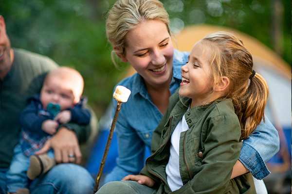 Familj som grillar marshmallows i skogen