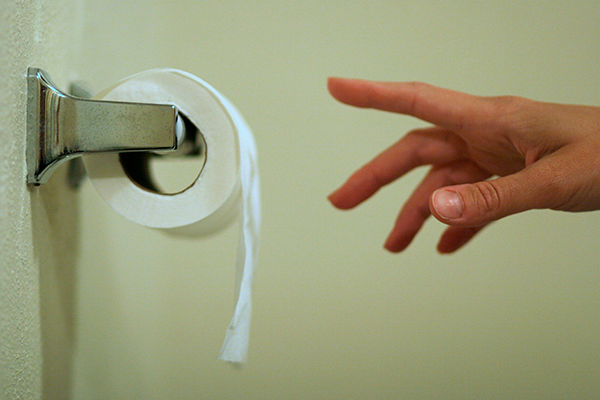 Kvinna sträcker sig efter toalettpapper