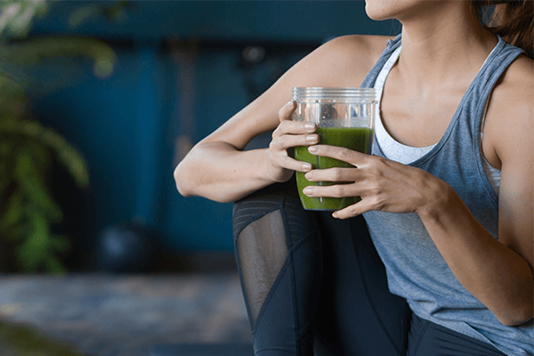 Kvinna dricker smoothie efter träningspass