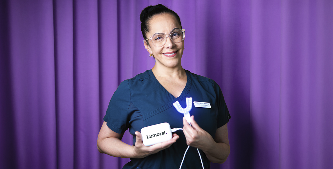 Tandv&aring;rdspersonal h&aring;ller Lumoral-enhet mot lila bakgrund.